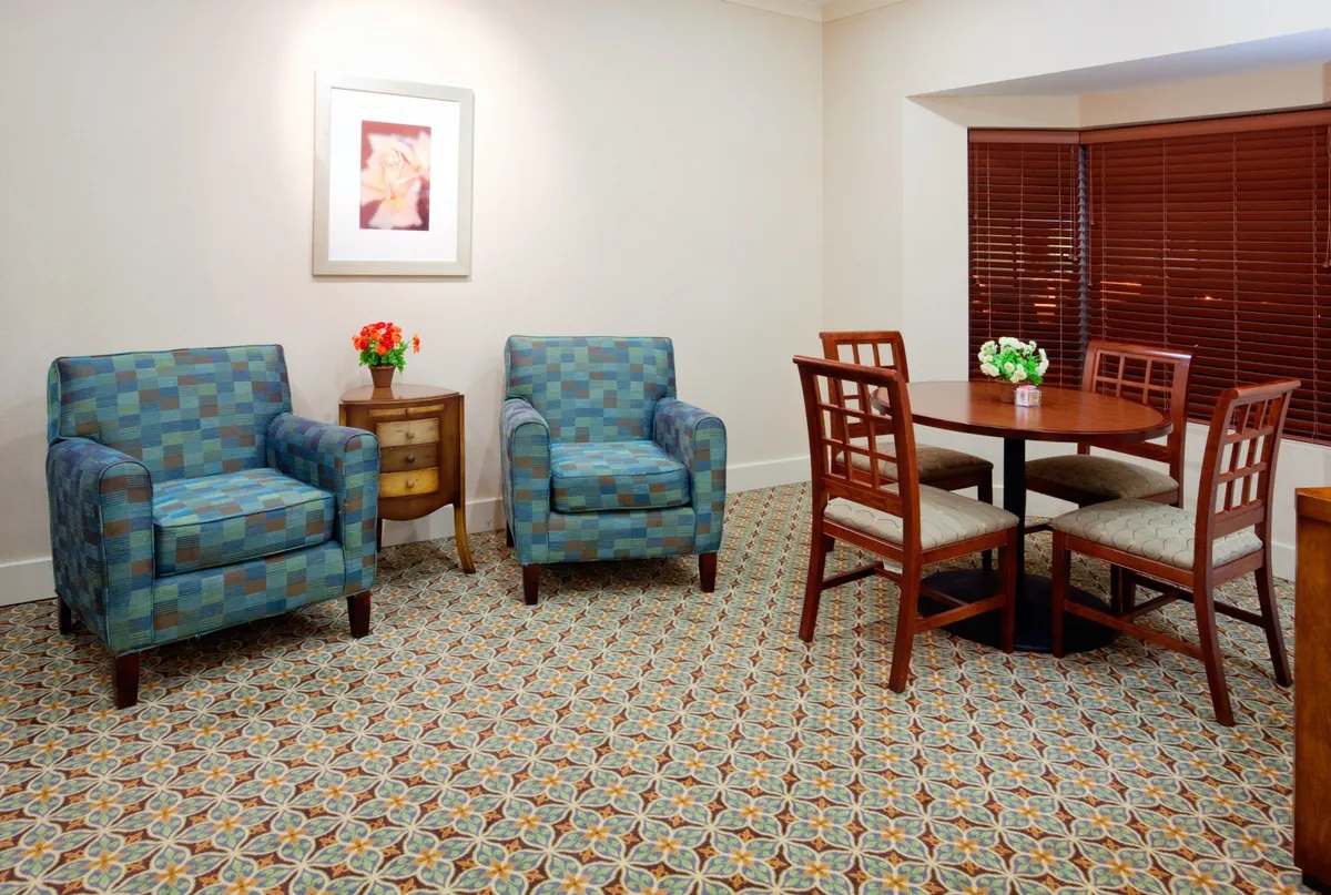 A welcoming interior space with several armchairs and a dining table set near a flower arrangement and framed artwork. The layout encourages casual conversation, enjoying refreshments, or gathering with friends and family in a home-like environment.